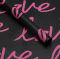 Roll of black paper with pink text on a black background