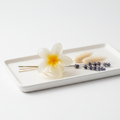 White rectangular plate with a white flower claw clip, lavender.