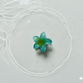 Green Small flower claw clip on a textured white surface