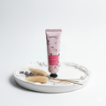 Cherry Blossoms Hand cream tube with floral design on a white plate with dried lavender and sticks