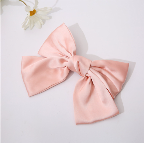 Large pink bow on a white background with a small white flower.