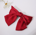 Red bow tie clip on a white background with a small white flower.